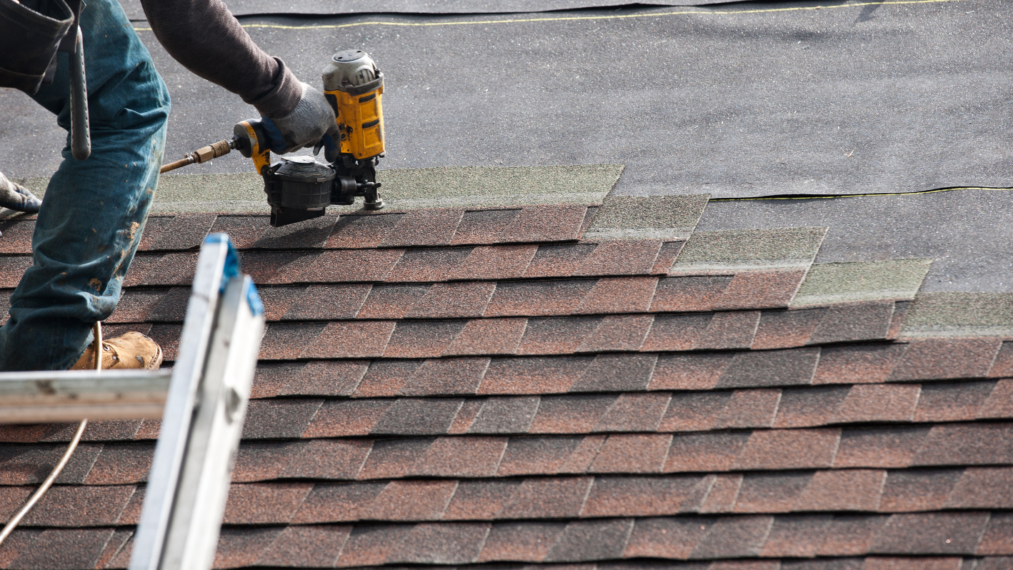 A man using a power drill on a roof