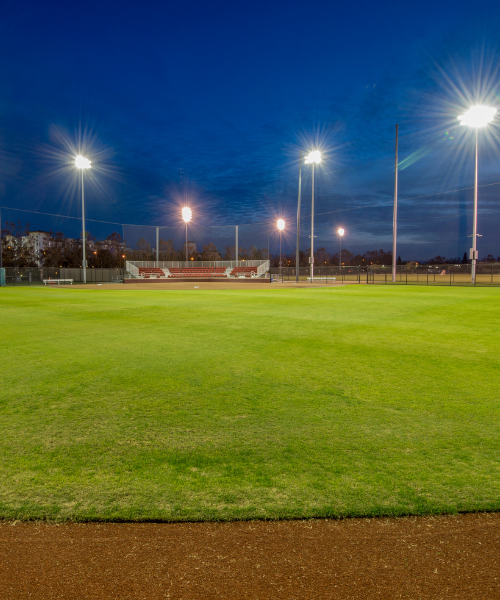 A baseball field at night with lights on